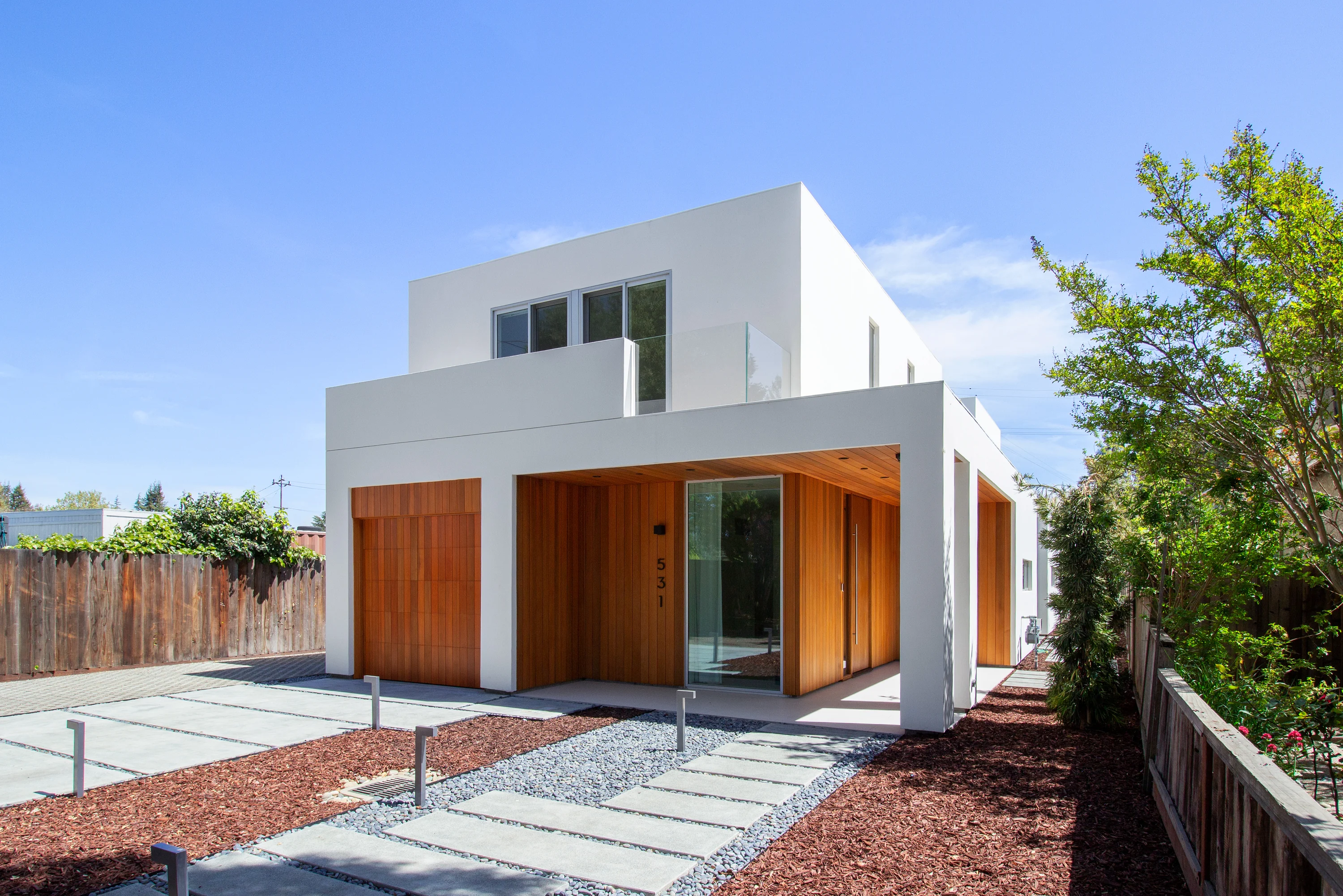 Front elevation of House of Two Courtyards with white stucco volumes and a cedar-lined entry
