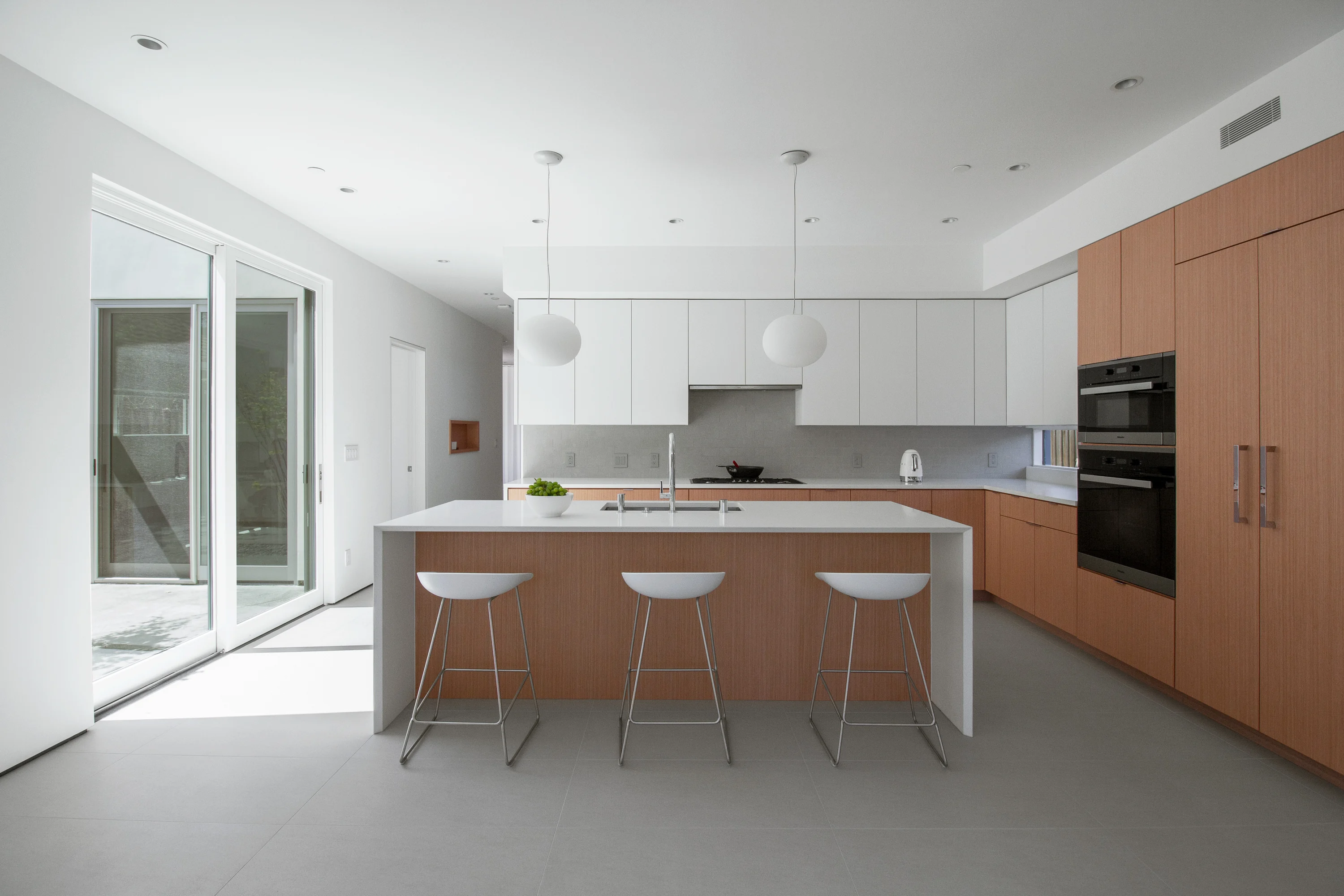 Kitchen with a large island, white cabinetry, and white oak detailing